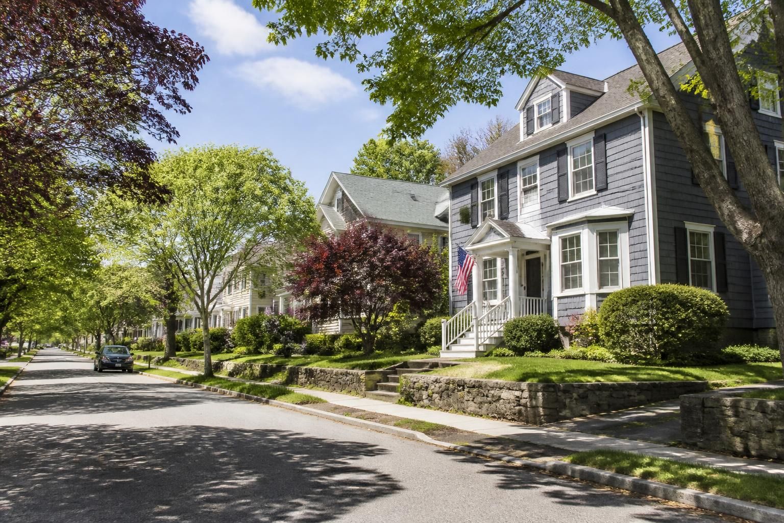 Quiet suburban neighborhood street with tidy homes and trees.
